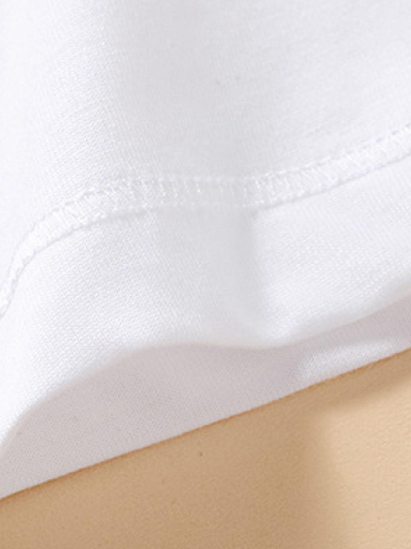 Close view of hem stitching on a plain white children's short sleeve polo shirt
