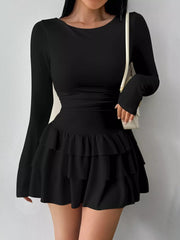 Black layered ruffle long sleeve mini dress worn front facing with a white shoulder bag
