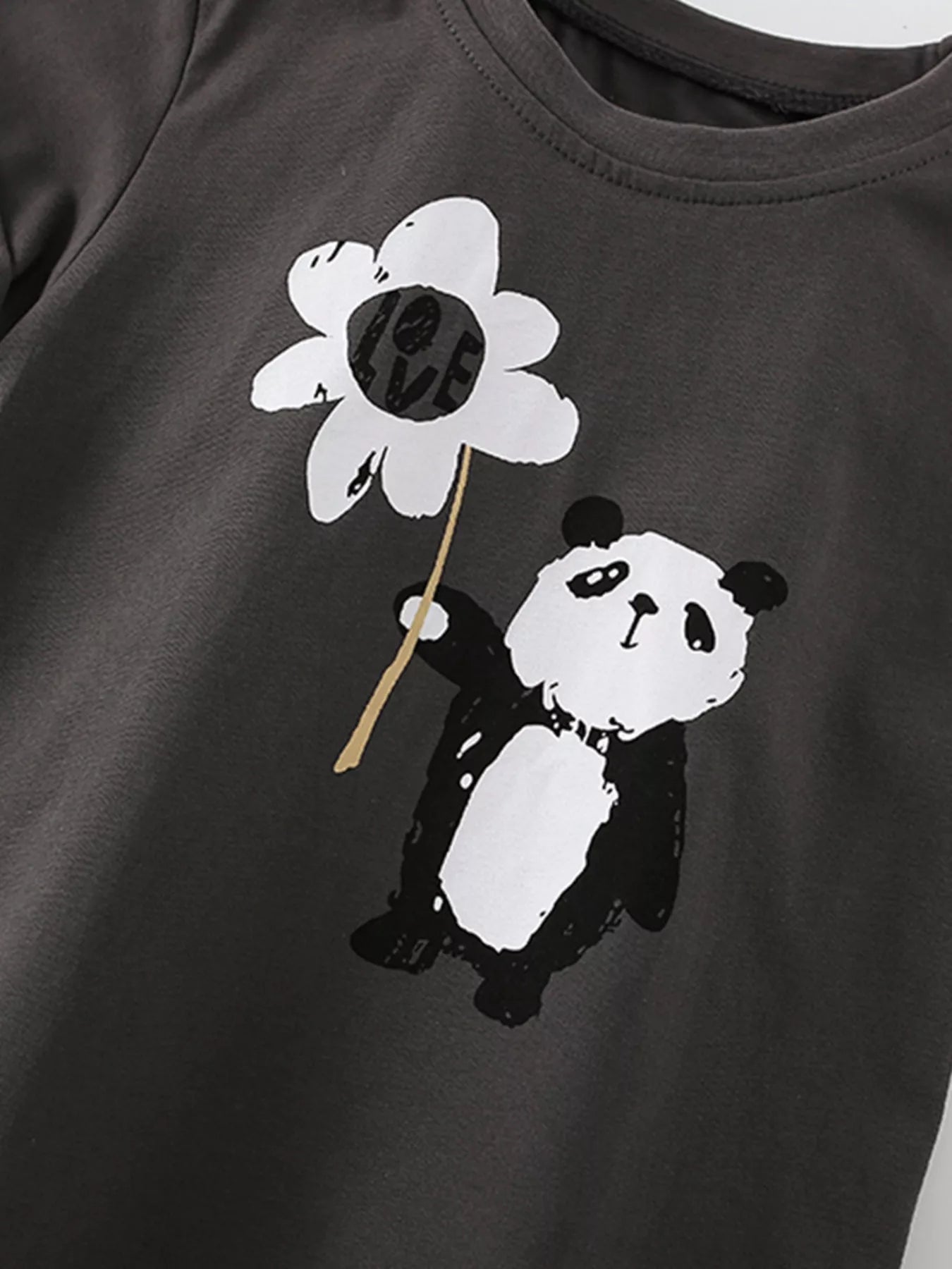 Angled close-up of the panda holding a white flower printed on dark gray fabric