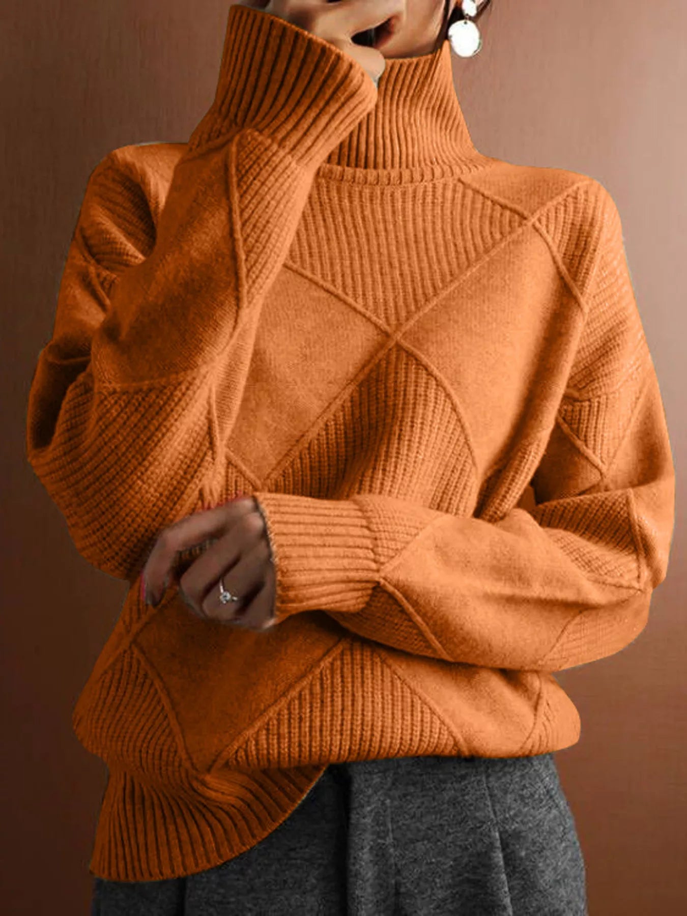 Front torso view of a tangerine turtleneck sweater with a tonal diamond pattern