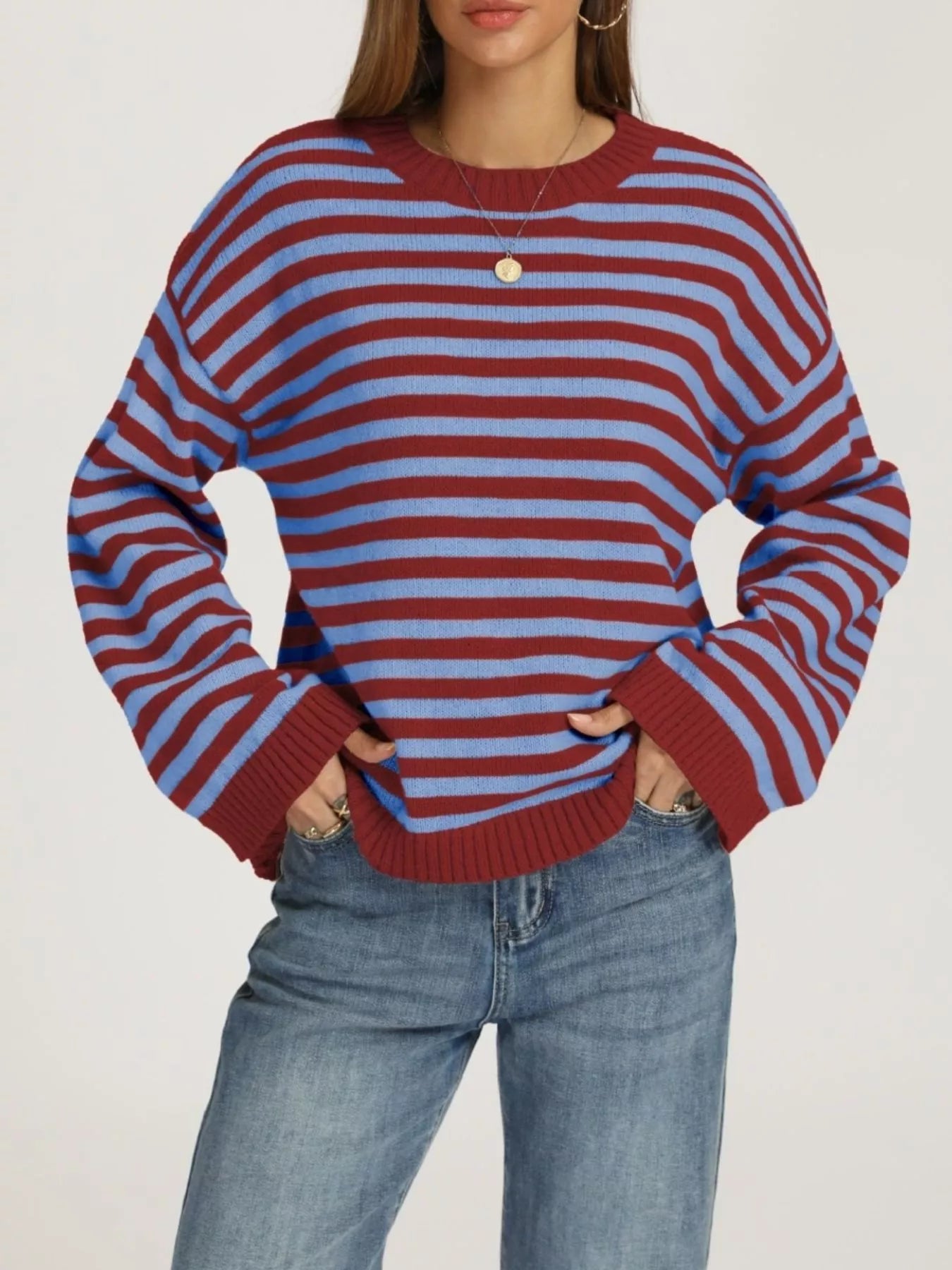 Front view of a red and blue striped dropped shoulder sweater with ribbed cuffs worn with jeans.