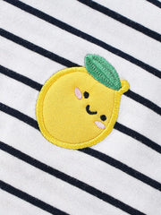 Close-up of the embroidered yellow lemon applique with green leaf on white navy striped fabric