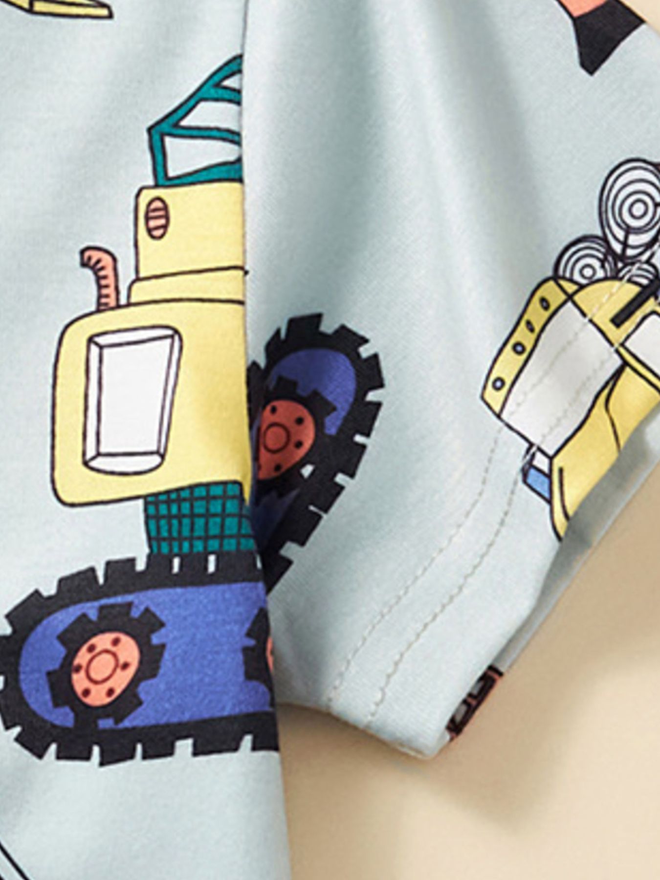 Close-up of the yellow excavator print and stitched sleeve hem on the children's tee
