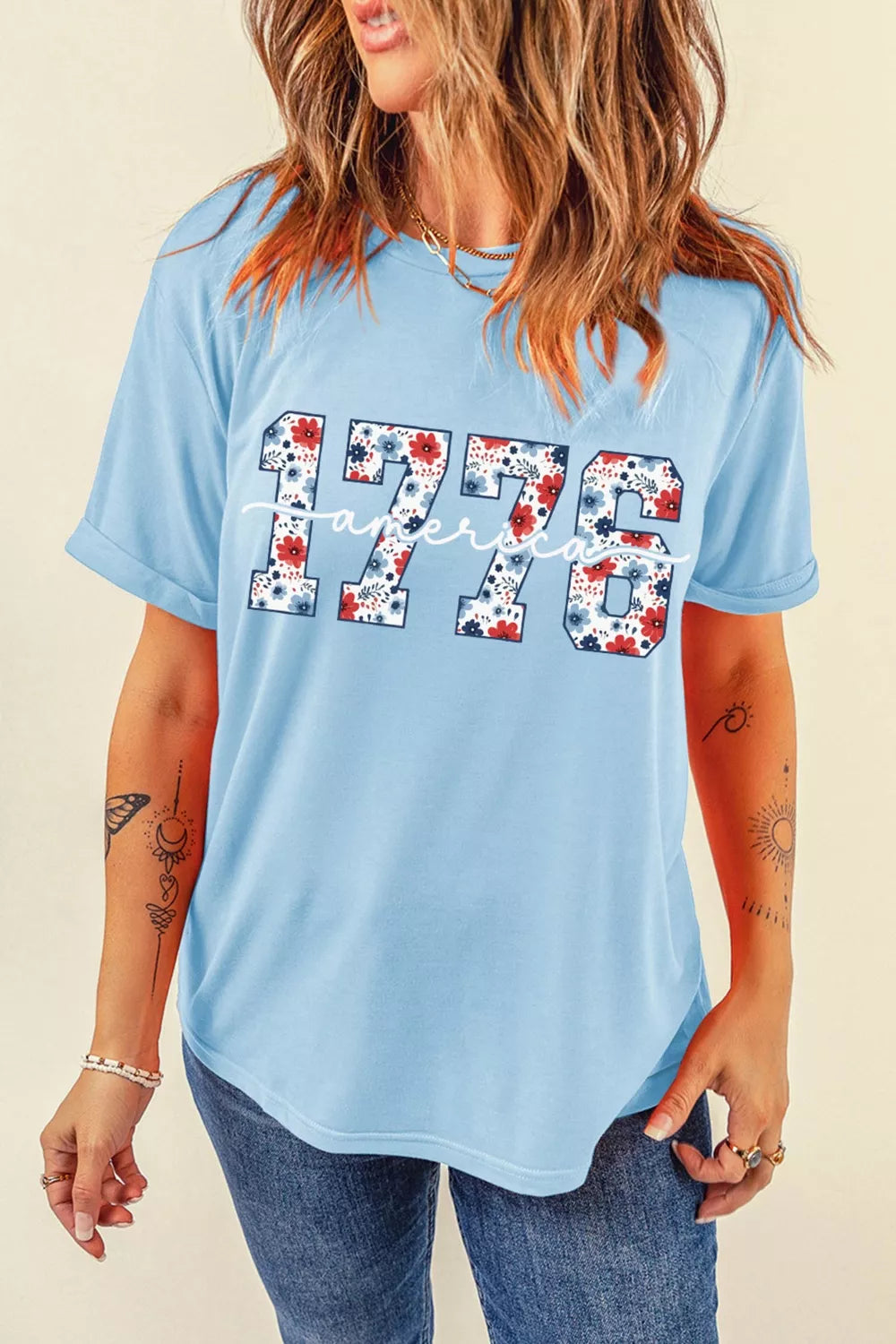 Relaxed light blue T-shirt featuring floral print “1776” and white “America” lettering on the front
