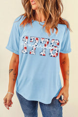 Relaxed light blue T-shirt featuring floral print “1776” and white “America” lettering on the front
