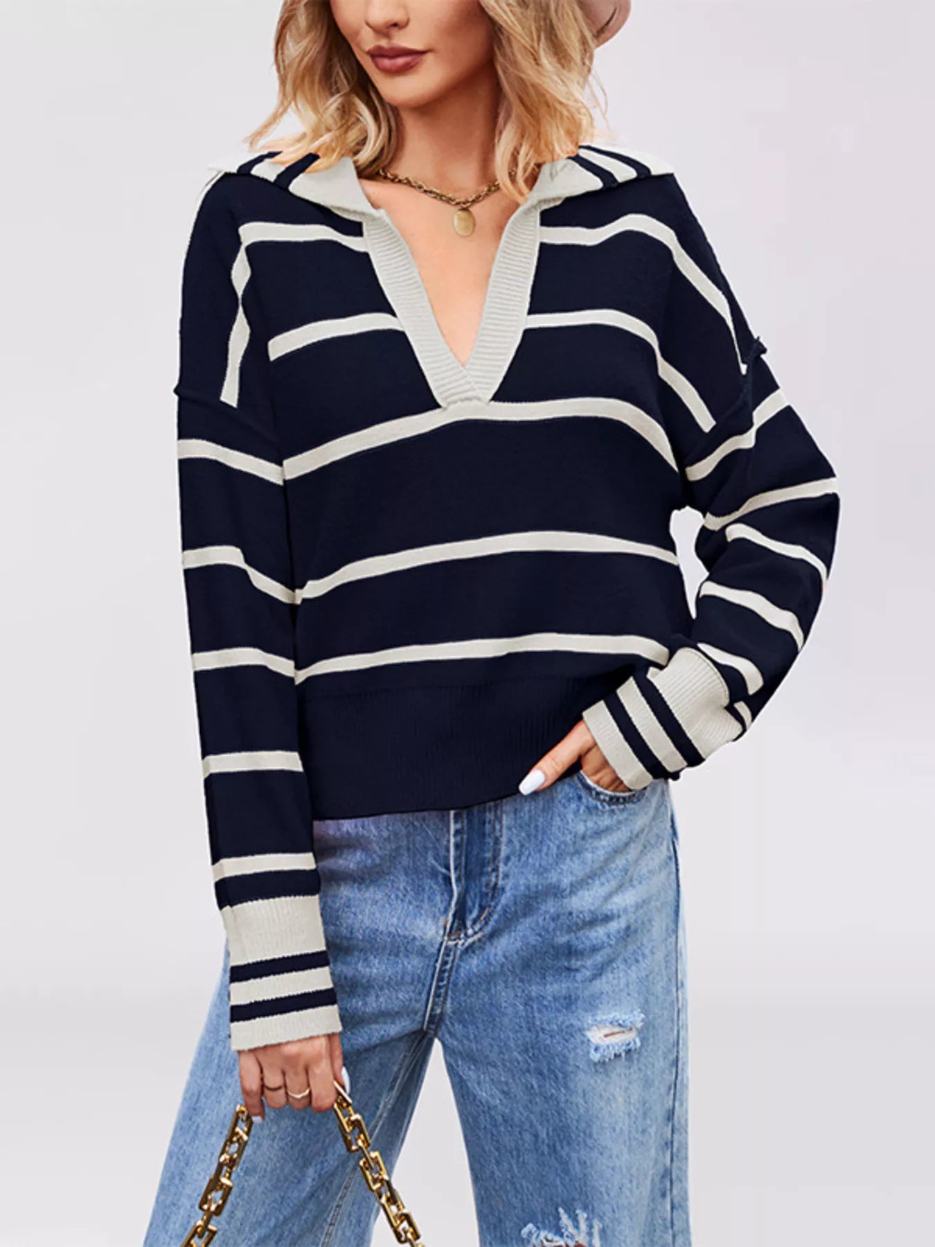 On-model front view of dark navy striped Johnny collar sweater holding a chain strap bag
