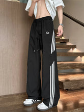 Men's black striped wide-leg pants with a drawstring waist and pockets.