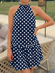 Navy blue polka dot halter neck mini dress worn standing outdoors with ruffled hem