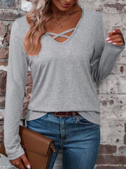 Gray long-sleeve T-shirt with crisscross V-neck detail, shown styled with jeans and a brown handbag.