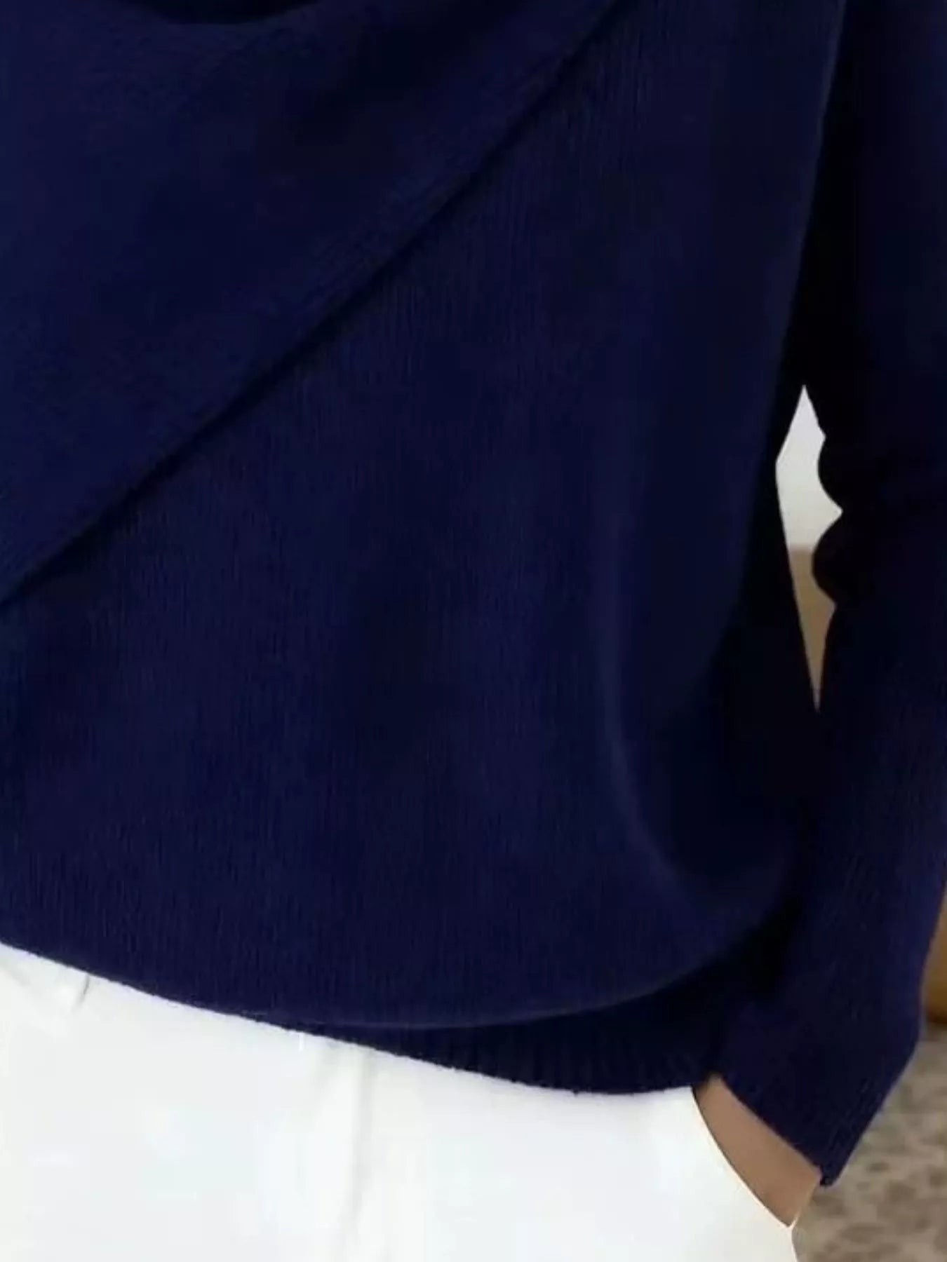 Close-up of the navy sweater lower body and long sleeve showing the ribbed hem and knit texture