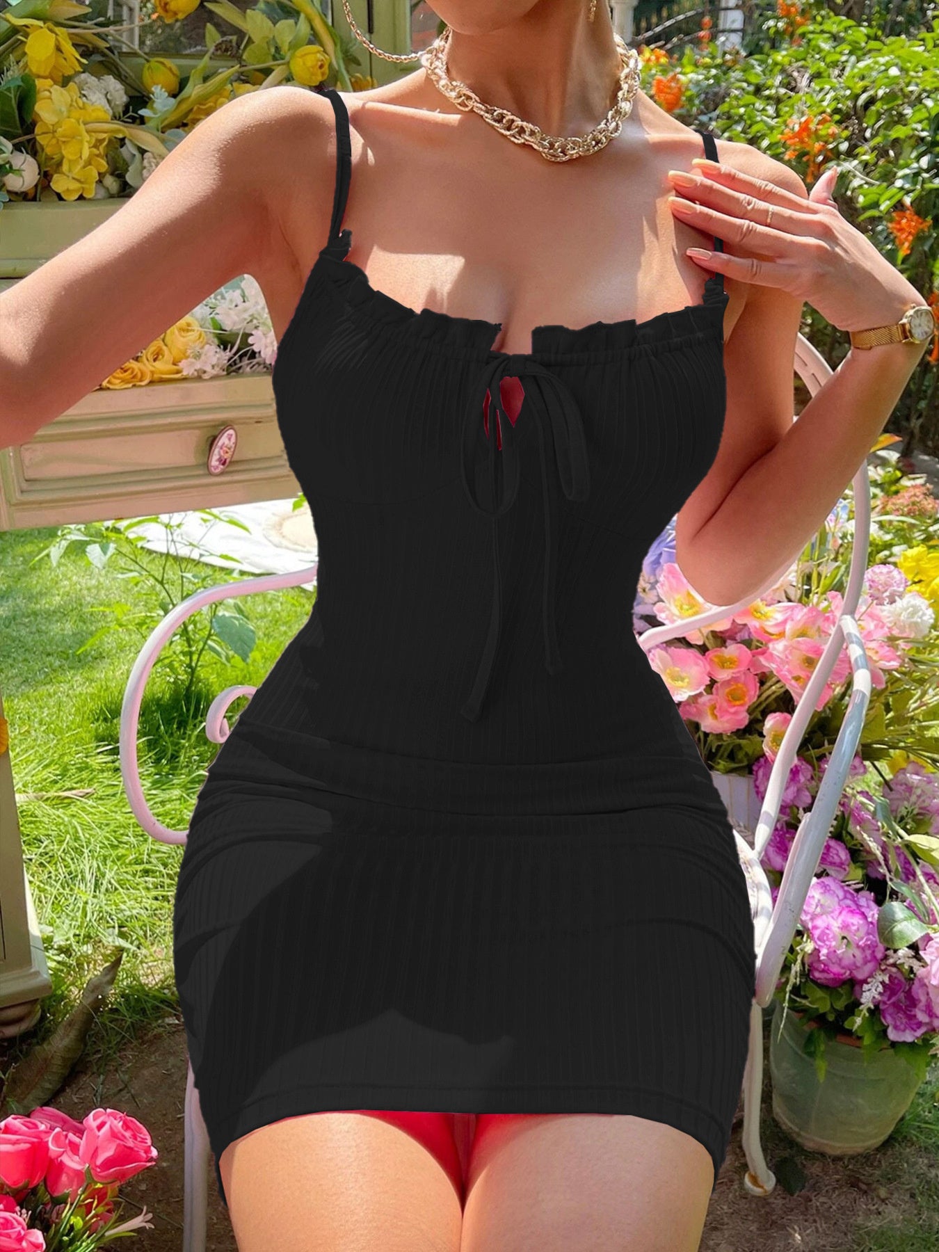 Black ribbed knit tie front mini dress worn seated in front view outdoors