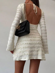 Model wearing pale apricot textured flare sleeve bodycon mini dress, back view showing open back