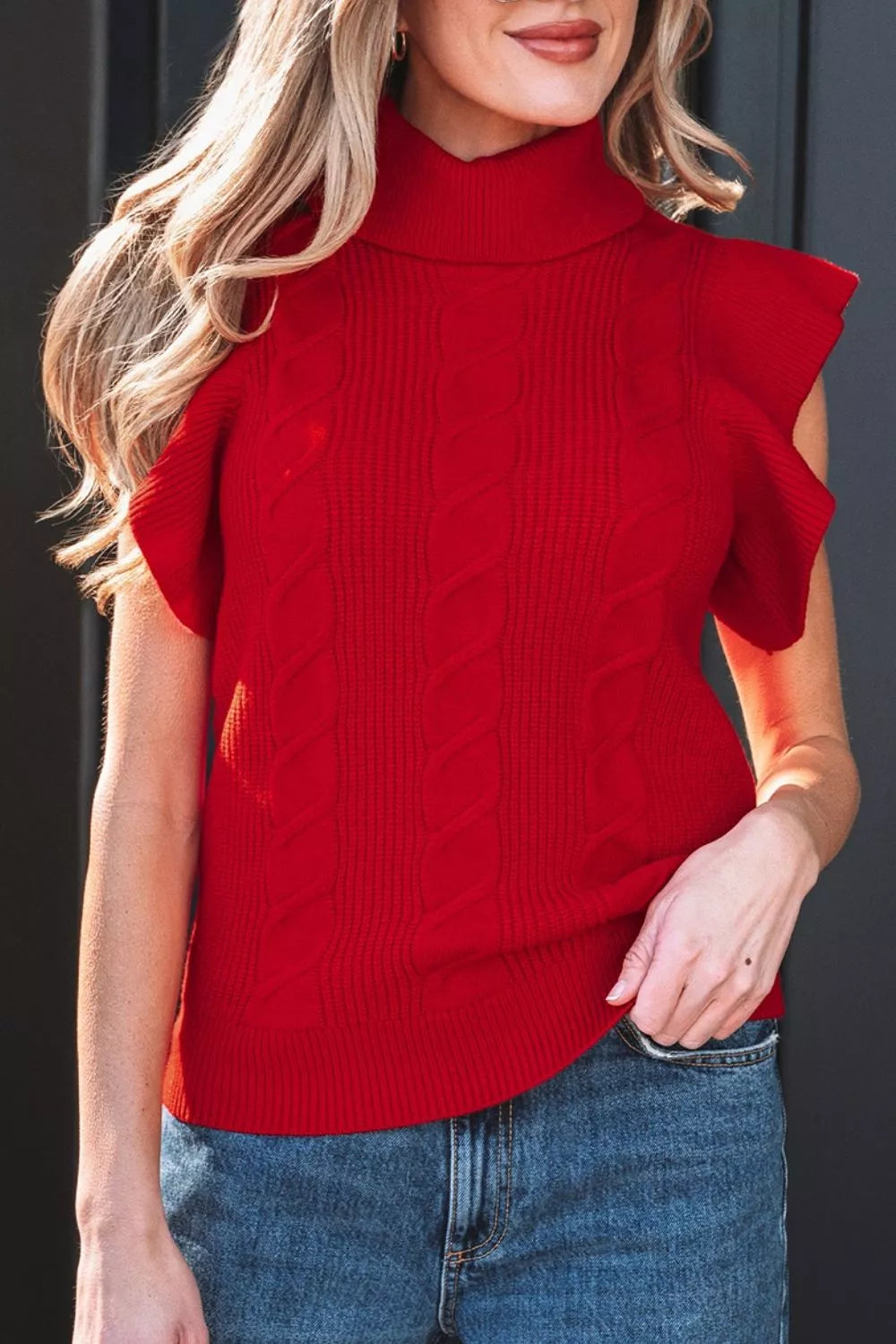 Front close view of a red cable knit turtleneck sweater with ruffled short sleeves