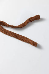 Close up detail of a brown knit tie from a beige sweater vest