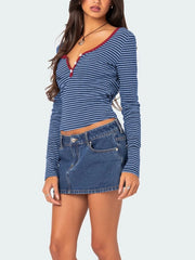 Three quarter front view of blue and navy striped long sleeve t shirt with deep red button placket