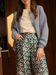 Full length view of open gray button down cardigan over a cream top and patterned trousers