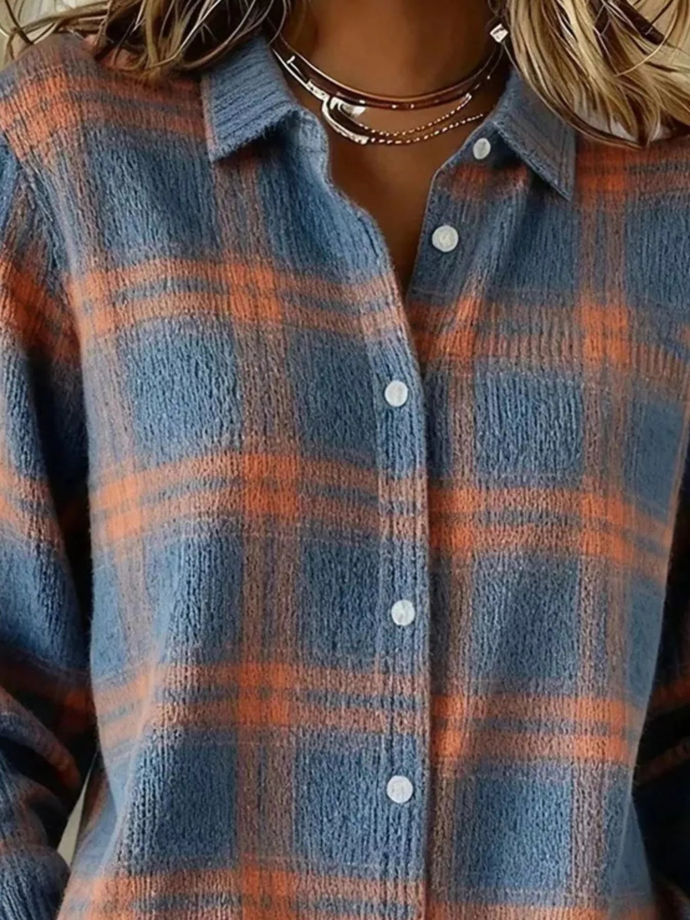 Close-up of the collar and button placket on a blue and orange plaid knit cardigan