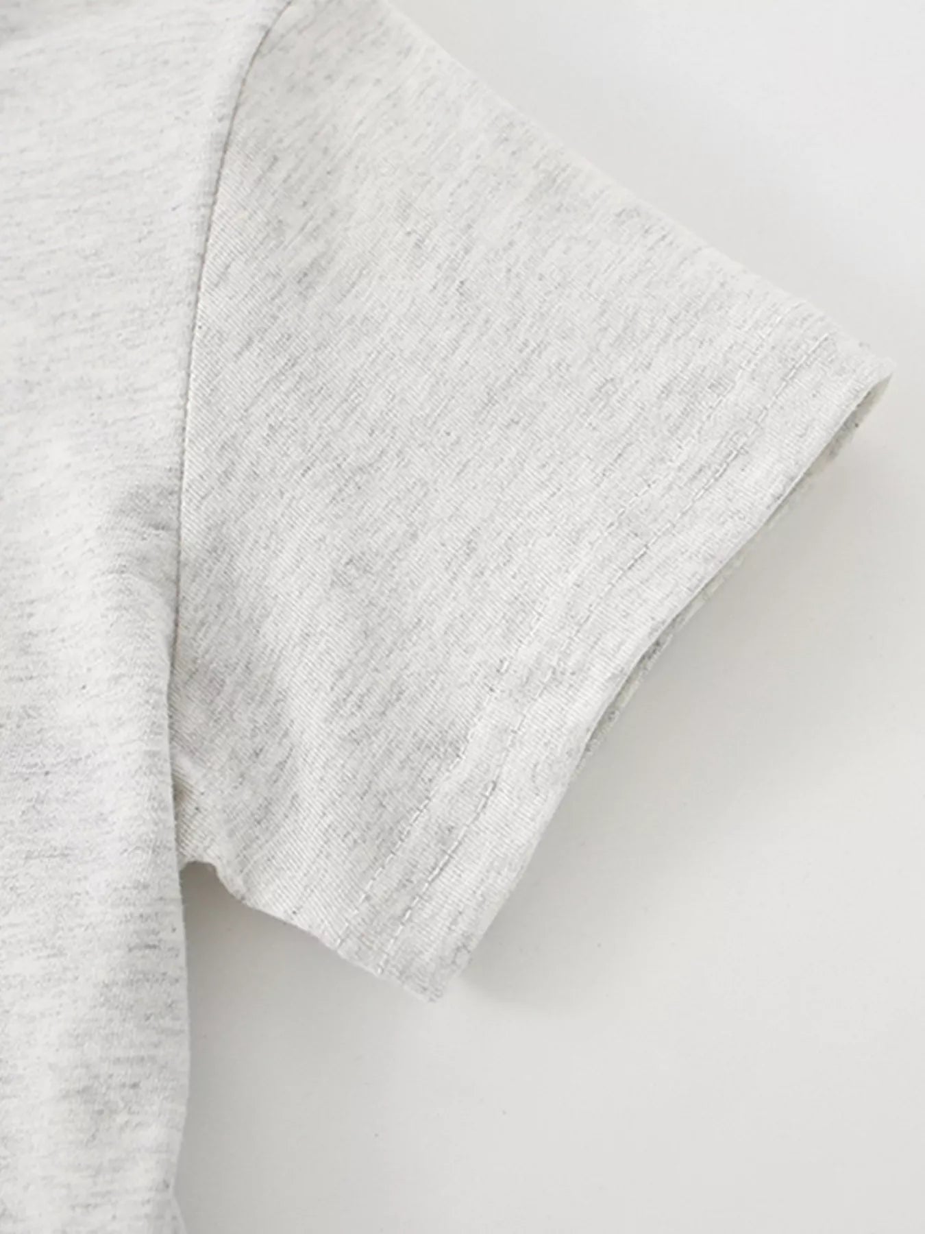 Close view of the short sleeve hem and stitching on the light gray children's T-shirt
