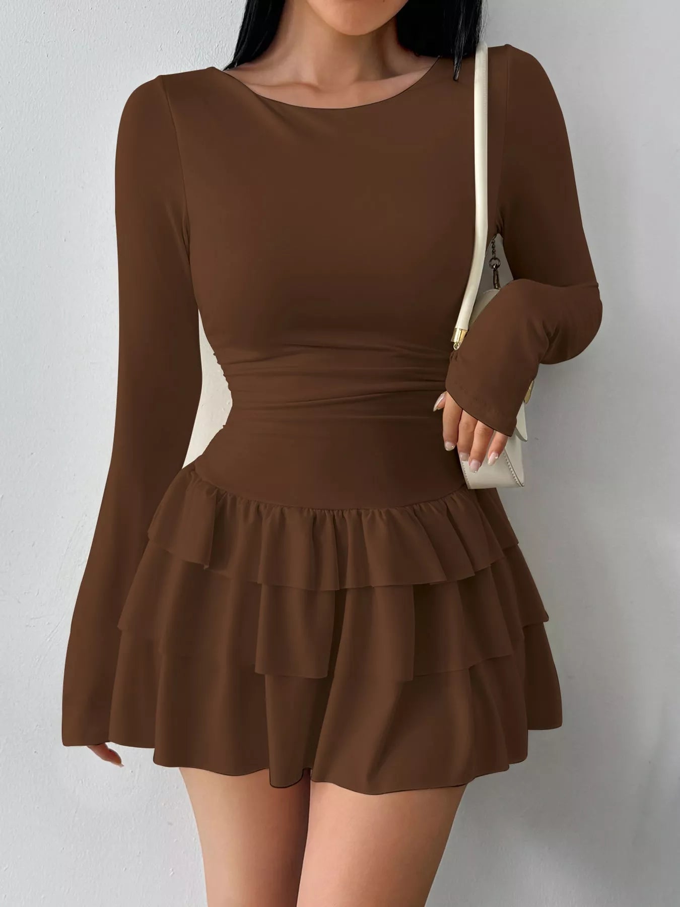 Coffee layered ruffle long sleeve mini dress worn front facing with a white shoulder bag