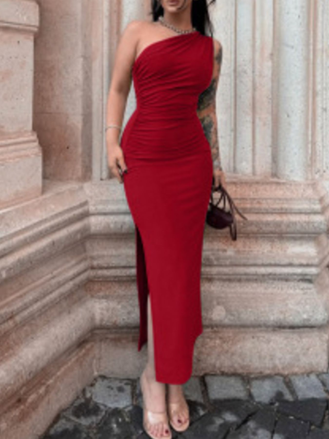 Model wearing deep red one shoulder ruched bodycon slit dress, front view outdoors