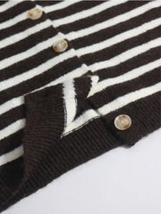 Close up detail of brown and white striped cardigan buttons and ribbed hem on flat surface