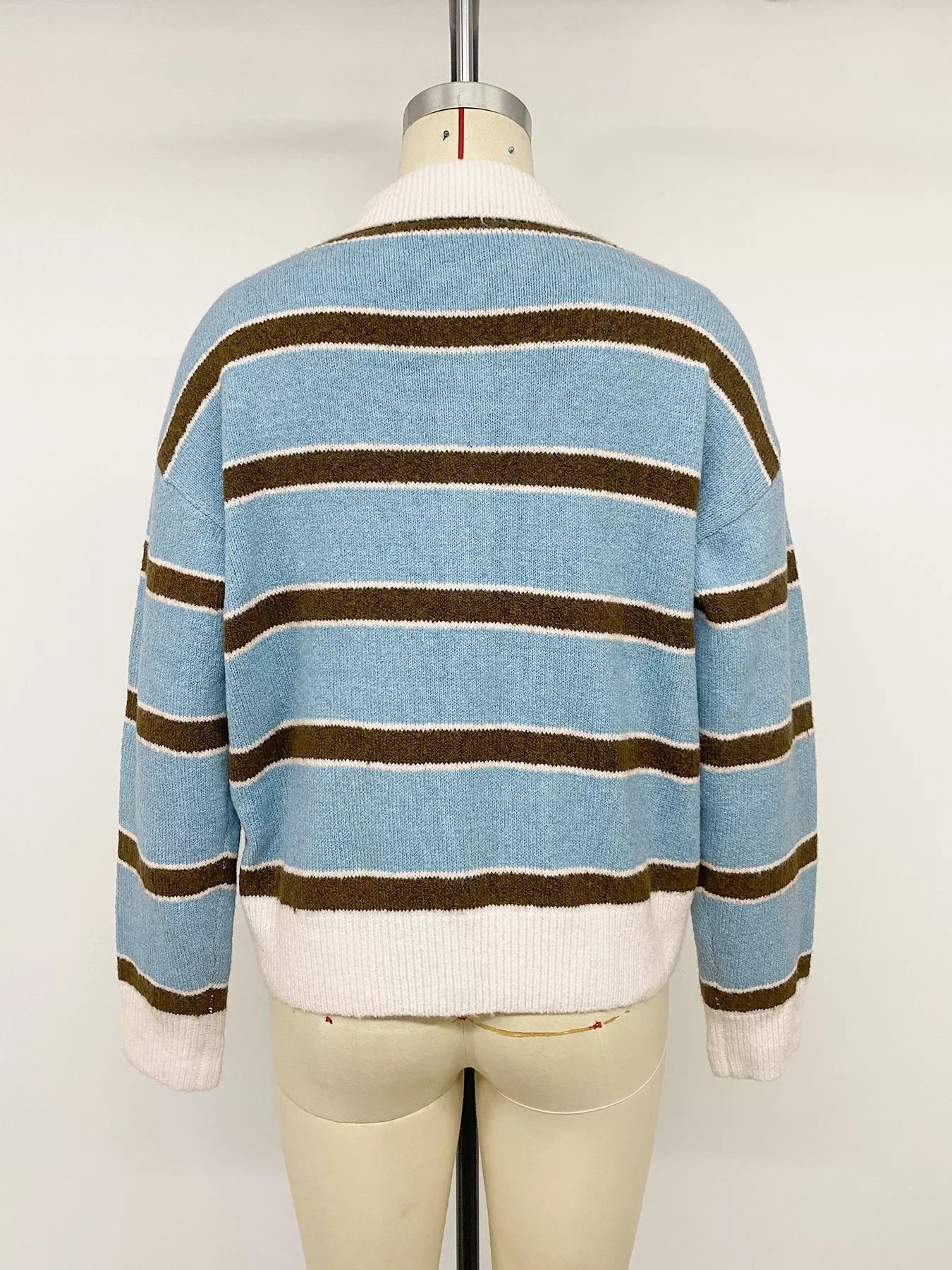 Back view of striped blue polo sweater on a mannequin, with cream collar and hem.