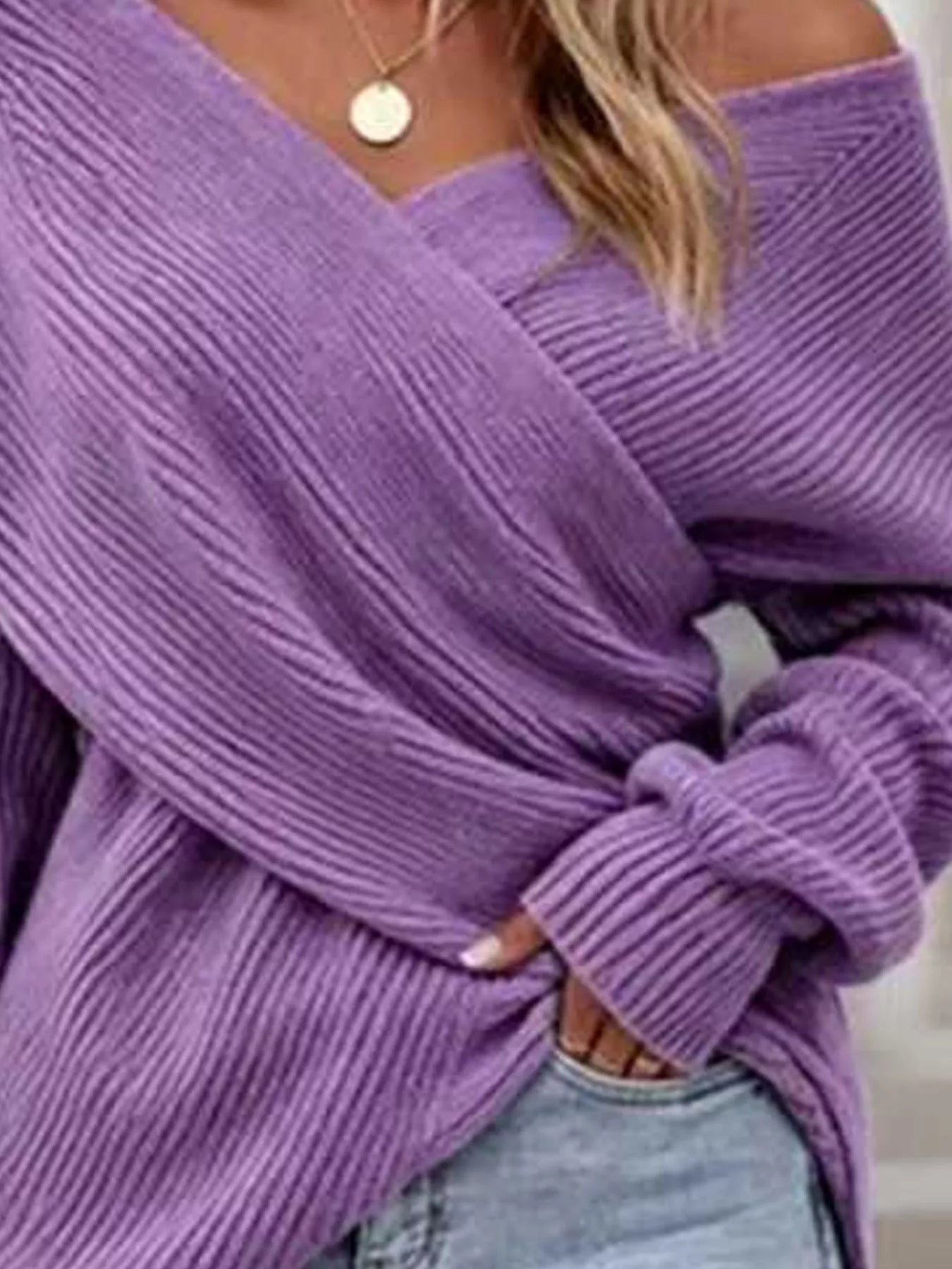Close front view of purple ribbed knit sweater showing crisscross V neckline detail.