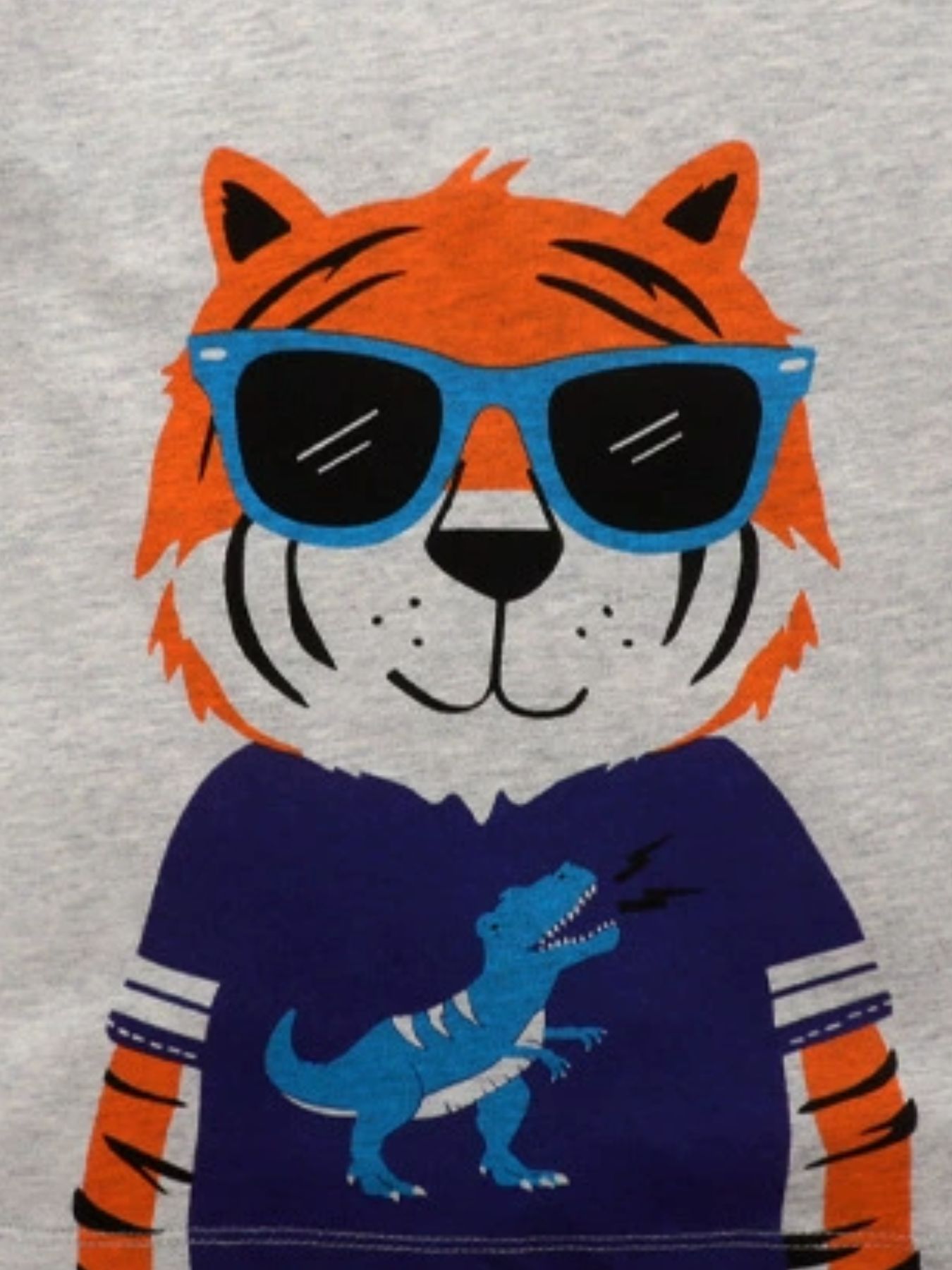 Close-up of the orange tiger face with blue sunglasses and a navy dinosaur shirt