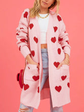 Front view of a pink longline cardigan with red hearts and front patch pockets