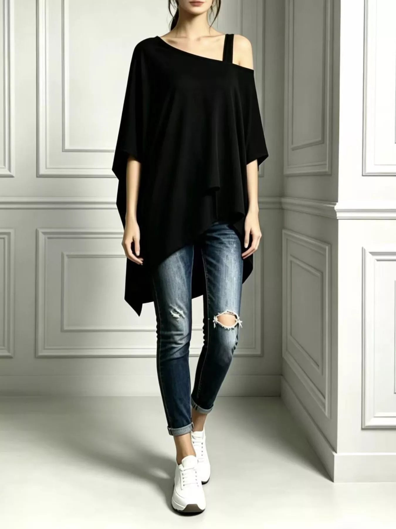 Black asymmetrical-neck short-sleeve tunic top styled with distressed cuffed jeans and white sneakers.