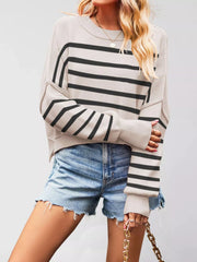 Front view of a beige sweater with black stripes, crew neck, and dropped shoulders worn with denim shorts.