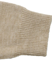 Close up of beige ribbed cuff on color block knit sweater sleeve.