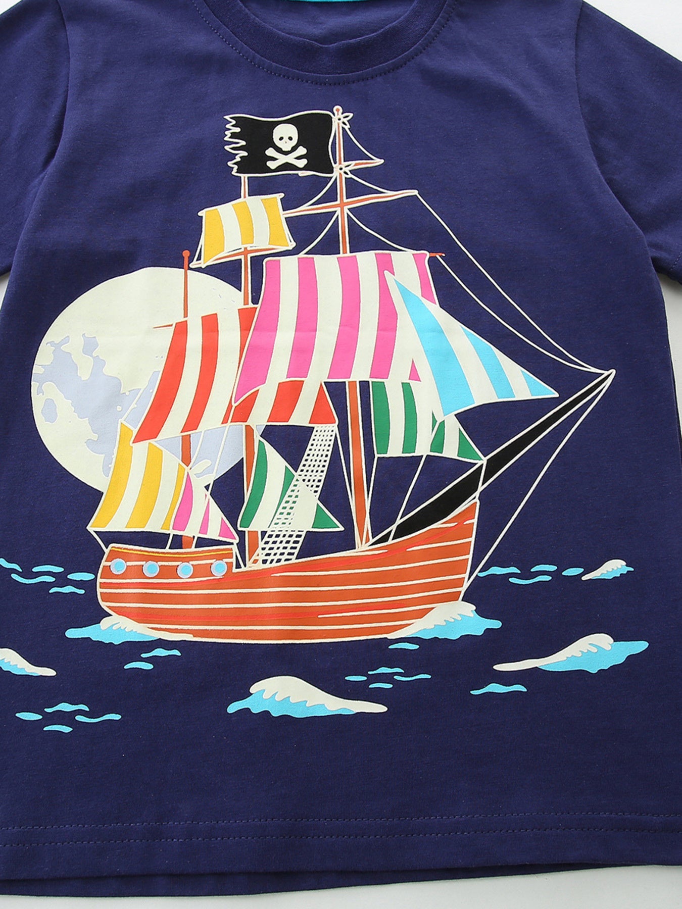 Close-up flat view of the colorful striped pirate ship graphic on dark navy fabric