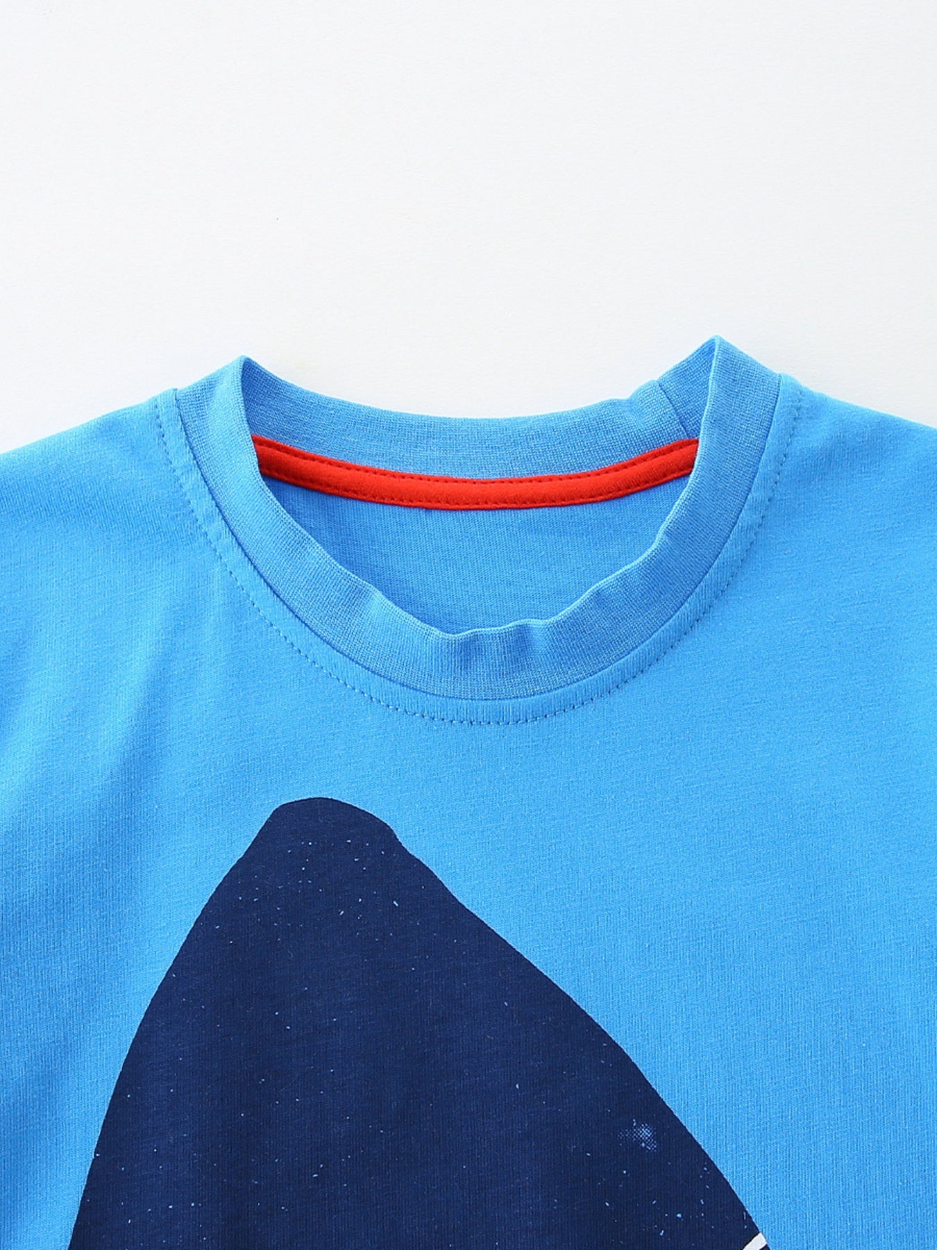 Close up of sky blue children's t-shirt round neckline with red inner trim stitching
