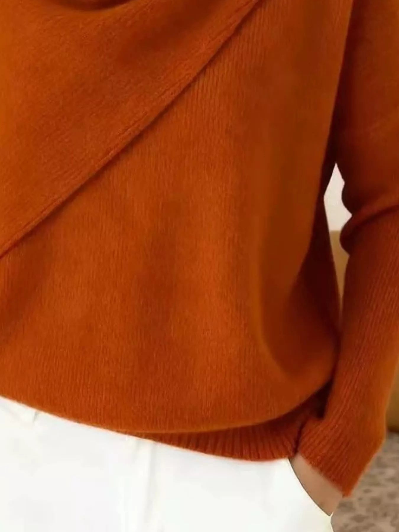 Close-up of the burnt orange sweater lower body and long sleeve showing the ribbed hem and knit texture