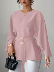 Pink round neck blouse front view holding black handbag with gold buckle belt