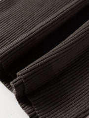 Close up of coffee brown ribbed hem and folded fabric on sweater vest