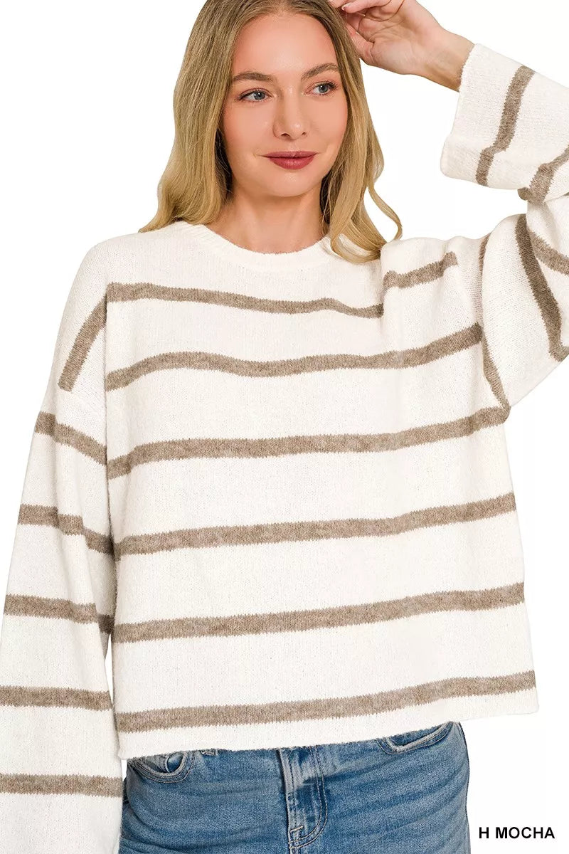 Front view of cream and mocha striped sweater with one sleeve raised.