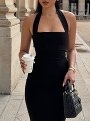Close front view of black halter neck bodycon midi dress holding cup and bag