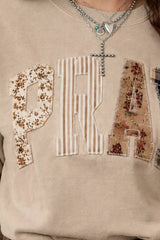 Close detail of khaki western sweatshirt showing floral, striped and plaid patch letters