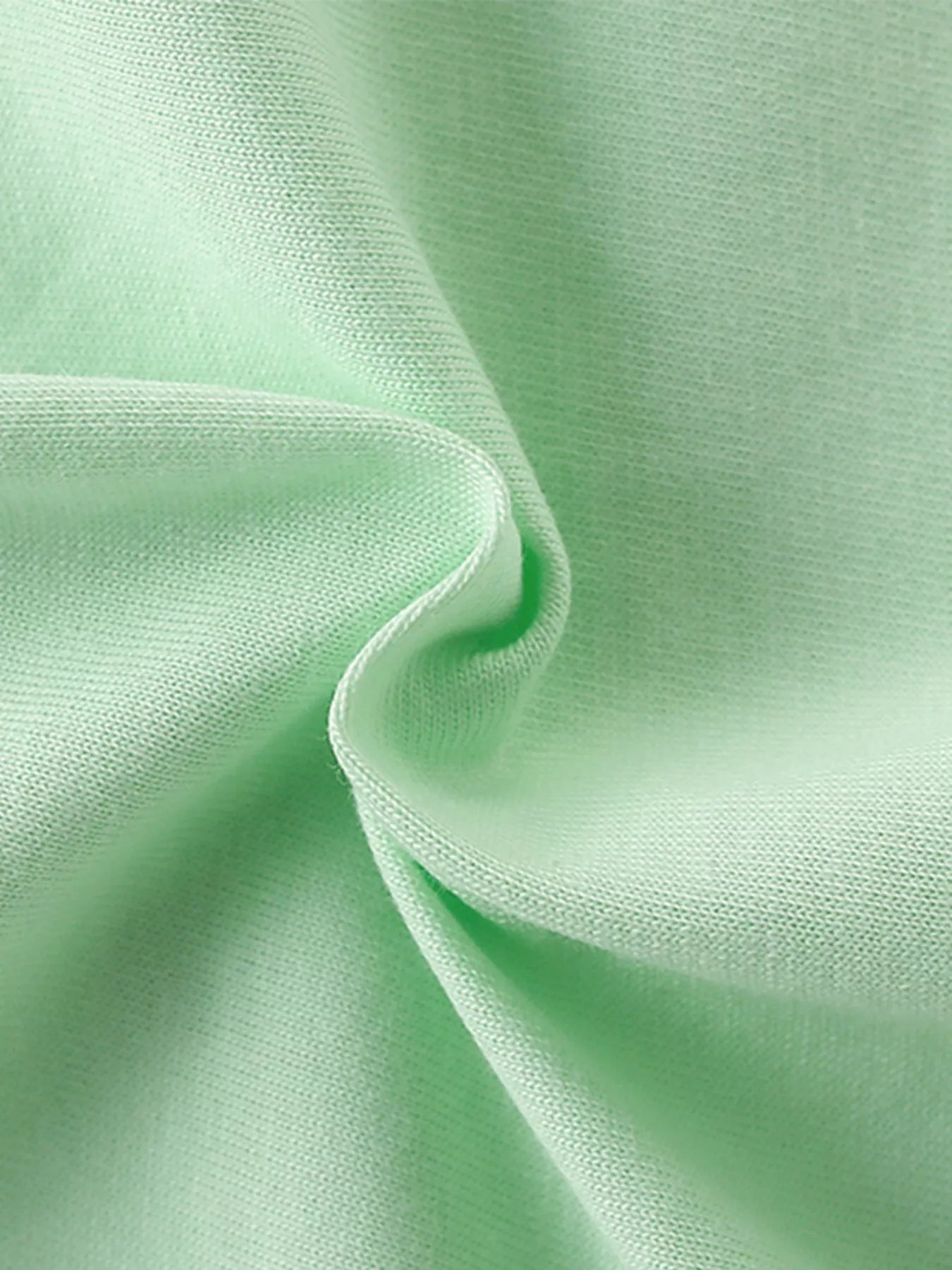 Close-up of soft light green cotton fabric texture with gentle folds