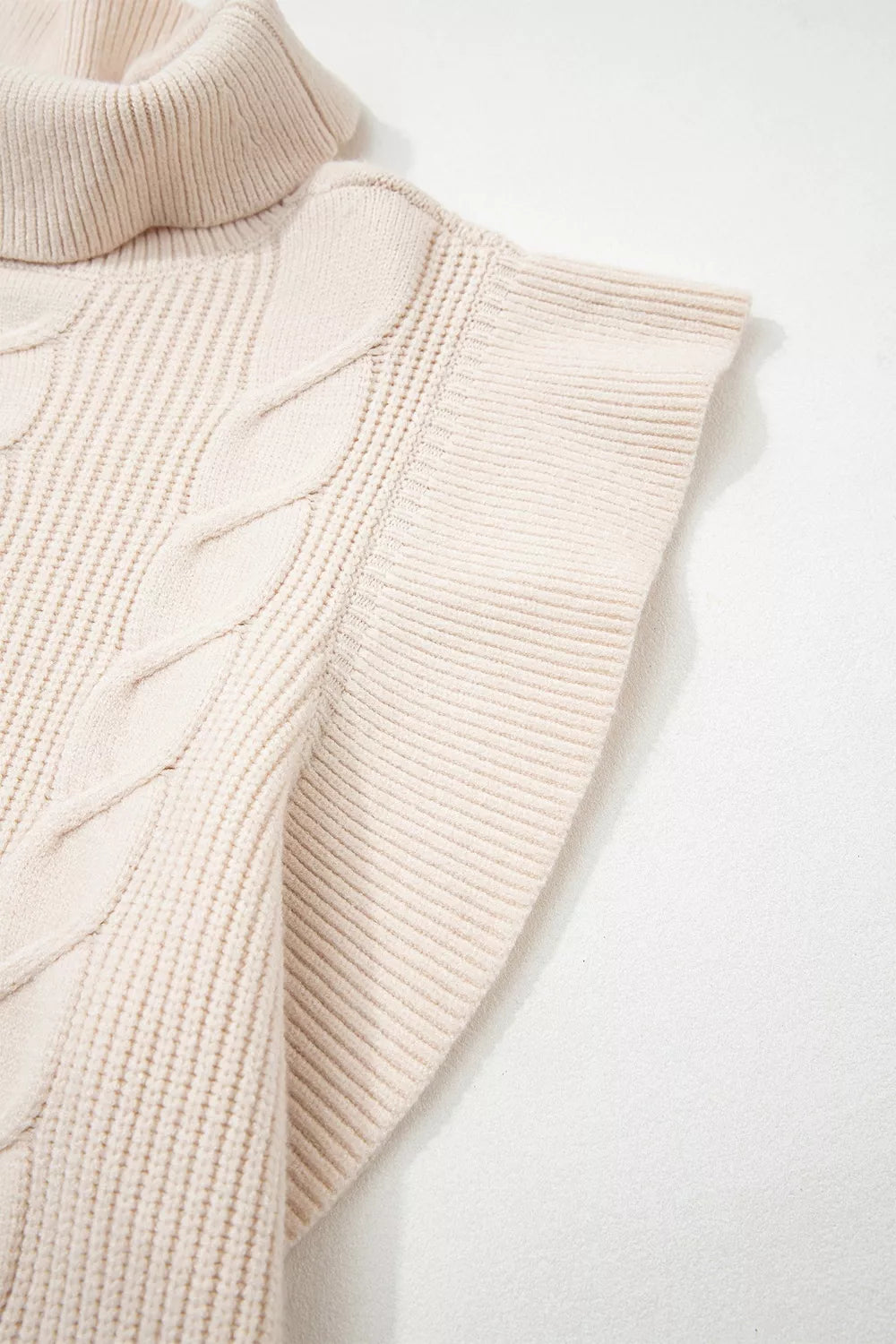 Close-up of the cream cable knit turtleneck sweater ruffled short sleeve