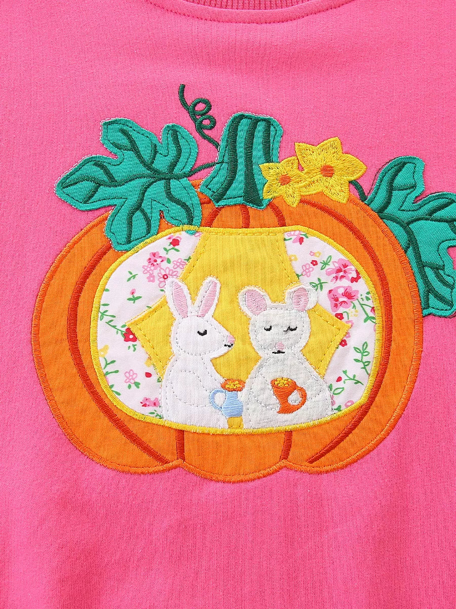 Close-up of the orange pumpkin applique with two white rabbits and floral fabric
