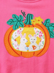 Close-up of the orange pumpkin applique with two white rabbits and floral fabric