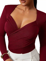 Close cropped front view of burgundy ruched surplice bodysuit with white trousers