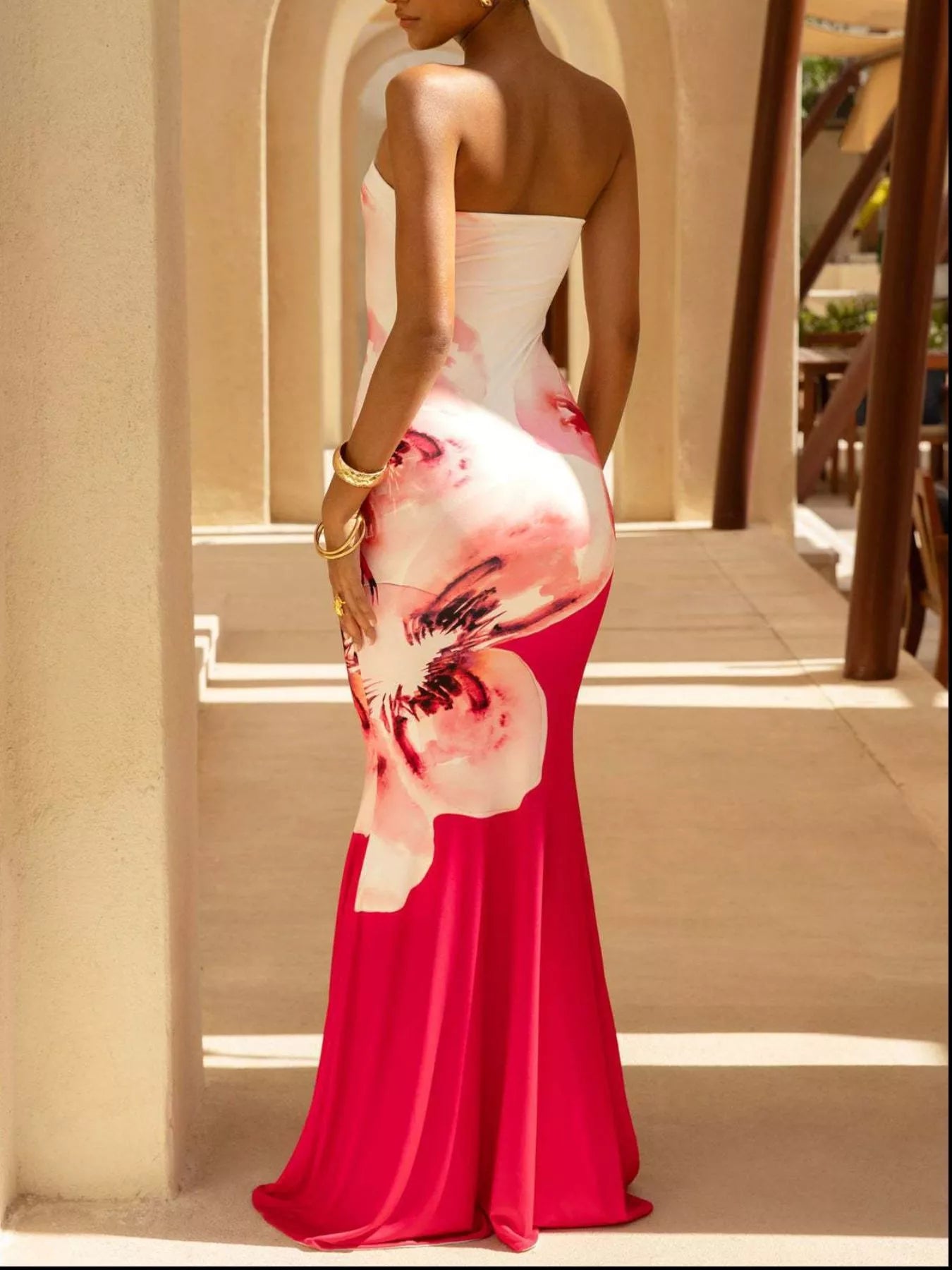 Model wearing strapless white and red floral tube maxi dress, back view outdoors