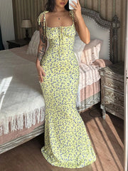 Model taking mirror selfie in yellow floral print bodycon maxi dress with tie straps and flared hem