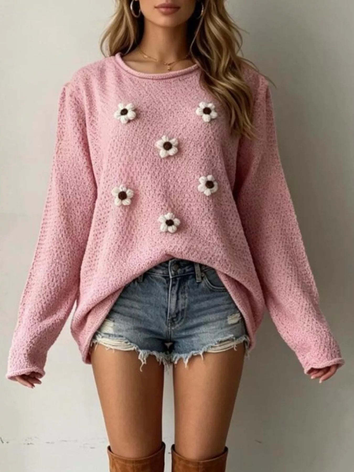 Front view of a pink textured knit sweater with white floral appliques and long sleeves