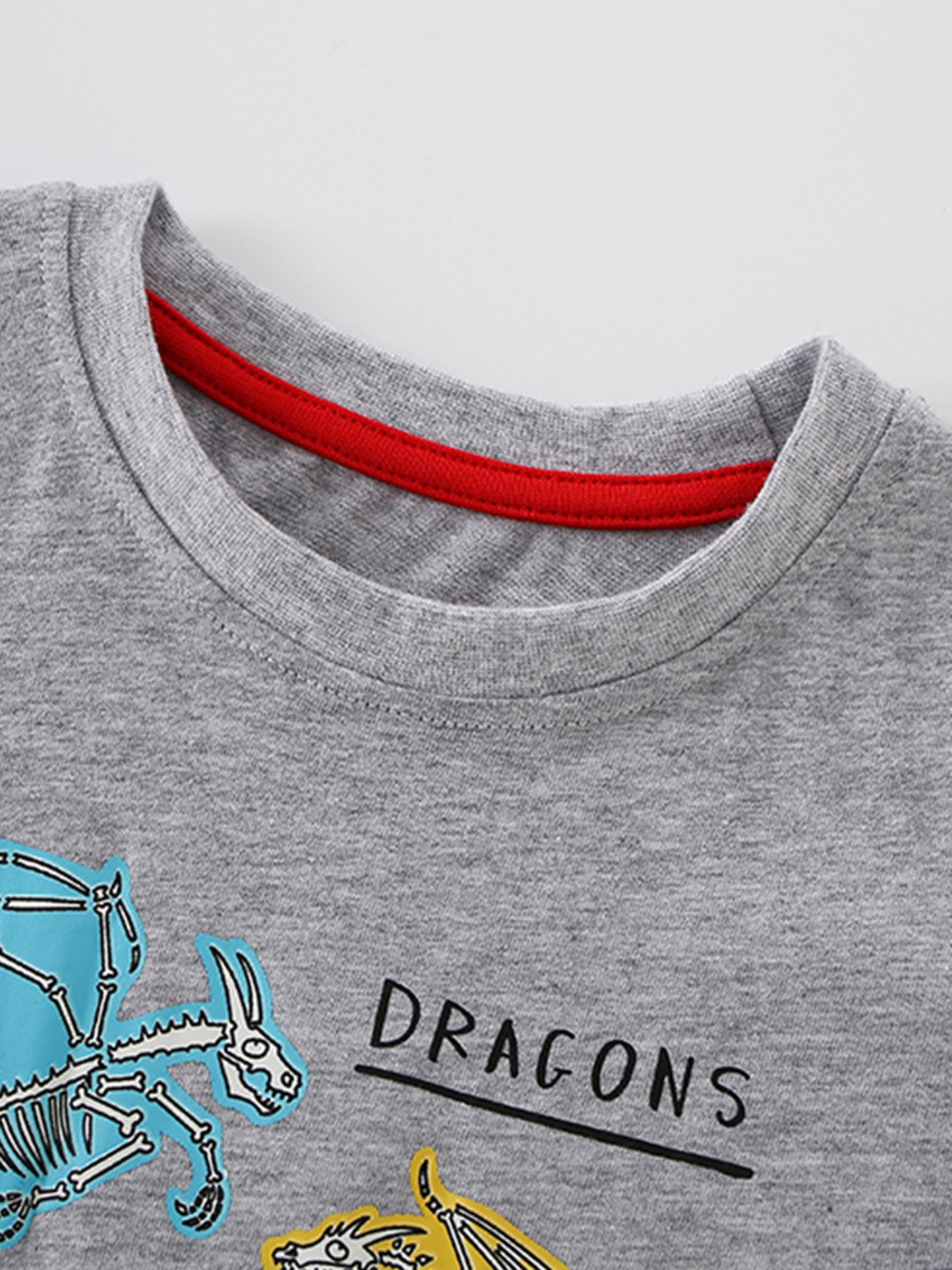 Close-up of the gray crew neckline with red inner trim on a children's dragon print T-shirt