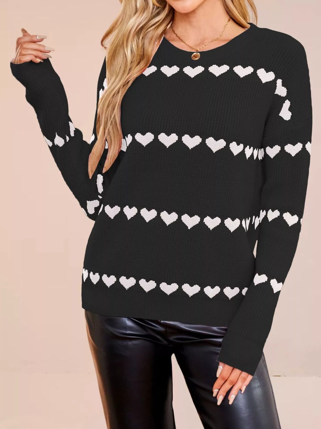 On-model front view of a black dropped shoulder sweater with rows of white hearts